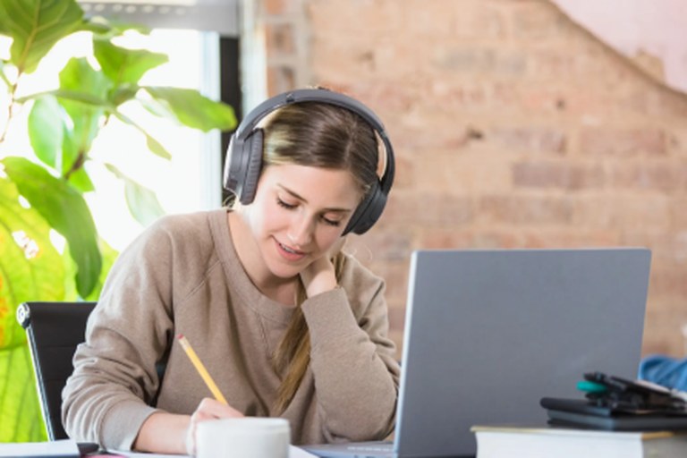 Student studying with headphones at a laptop